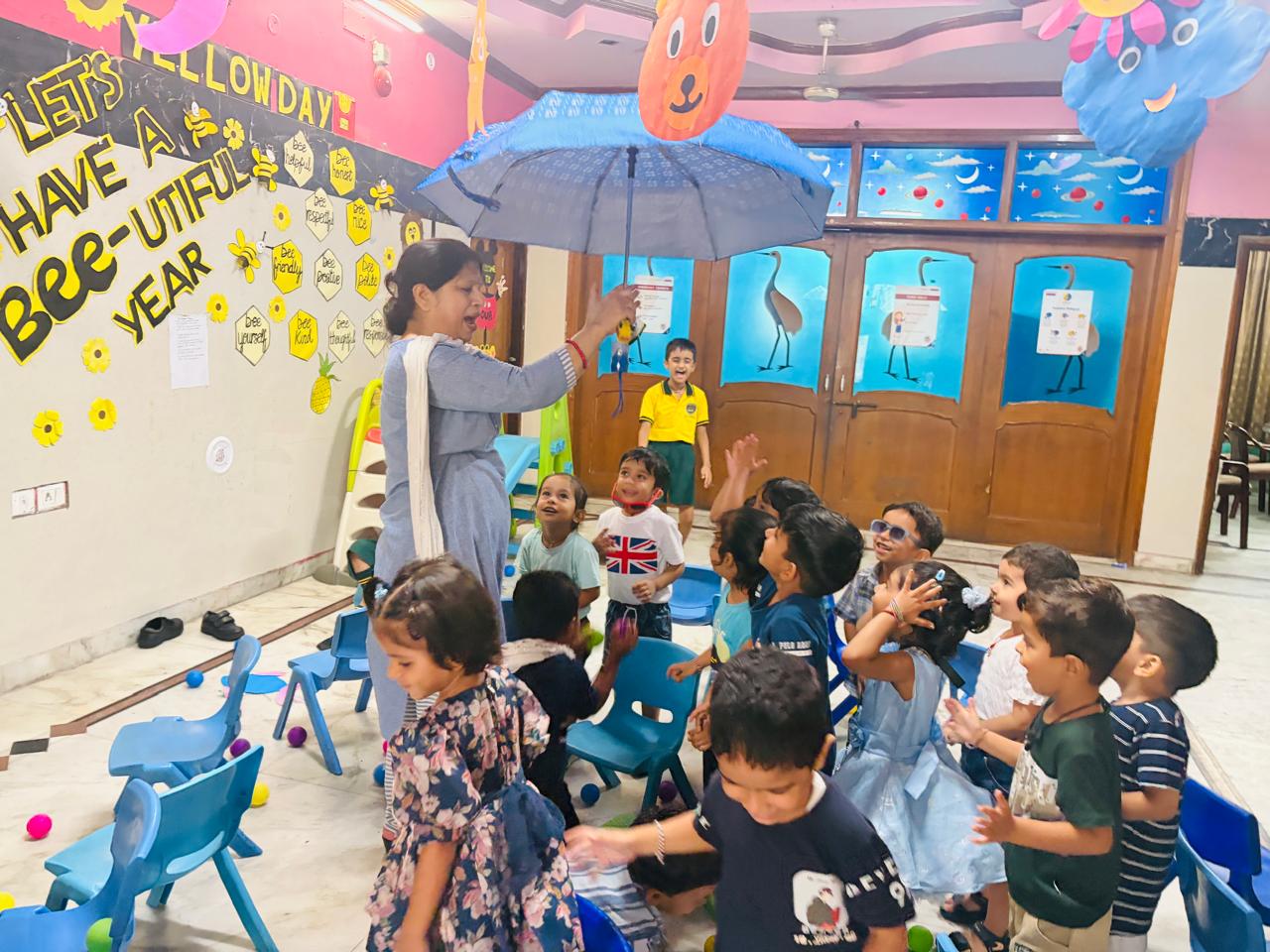 Teacher and students playing indoors with umbrellas at Prakriti